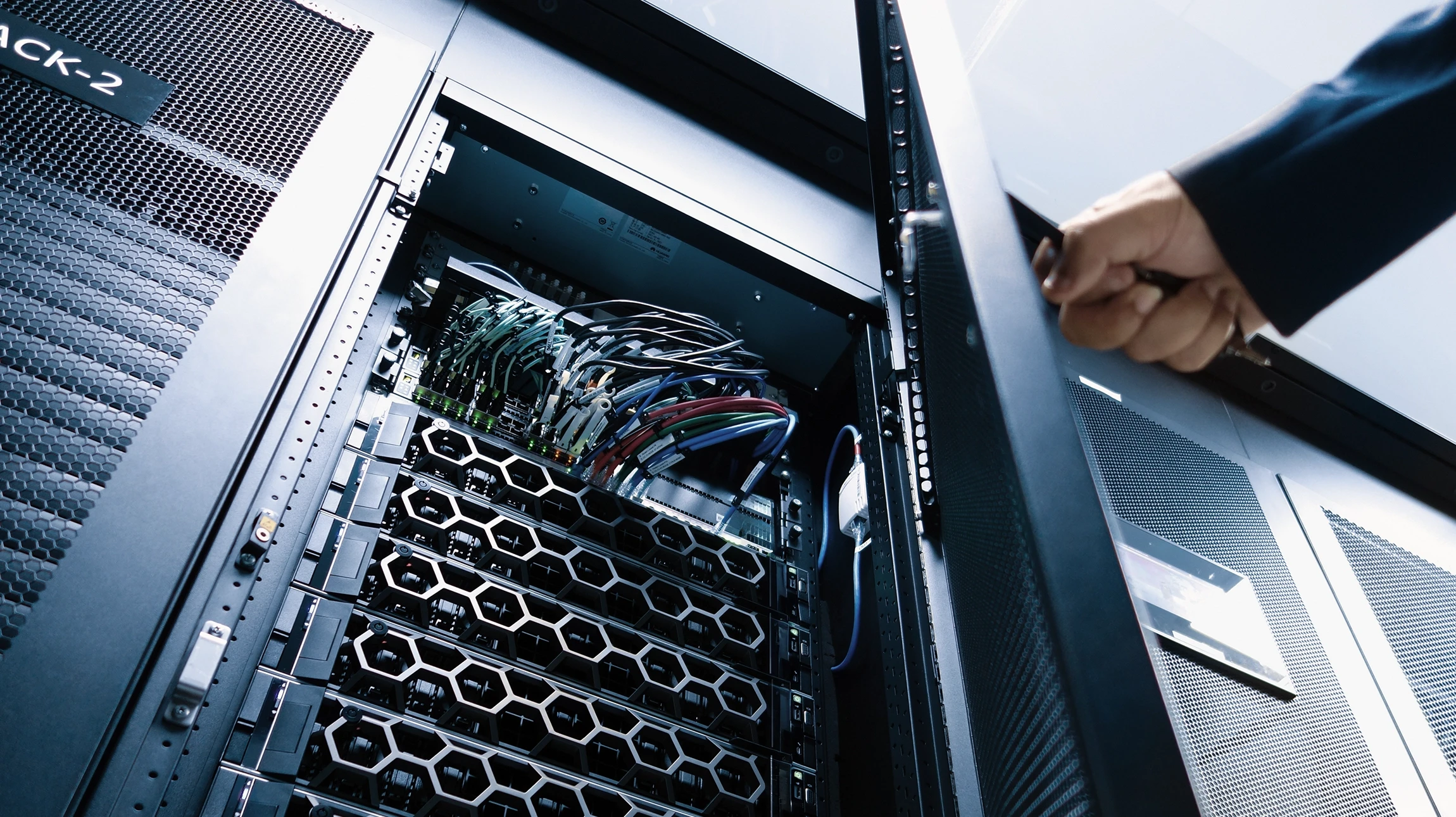 Int&eacute;rieur de datacenter avec technicienne en chemise bleue utilisant une tablette tactile pour surveiller les &eacute;quipements r&eacute;seau