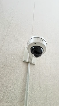 Sc&egrave;ne ext&eacute;rieure r&eacute;sidentielle avec cam&eacute;ra de surveillance d&ocirc;me PTZ au premier plan surveillant une maison moderne &agrave; deux &eacute;tages