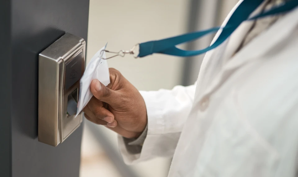 Une main utilise un système de contrôle d'accès biométrique à reconnaissance d'empreintes digitales, monté sur une porte en bois